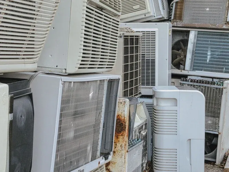 Old air conditioning units stacked for radiator and coil recovery.