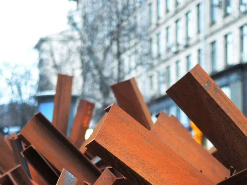 Heavy steel plate and beam offcuts stacked outside for the grab.